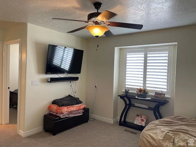 bedroom featuring ceiling fan, light colored carpet, and a textured ceiling