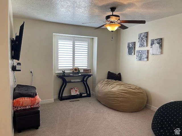 sitting room with ceiling fan, light carpet, and a textured ceiling
