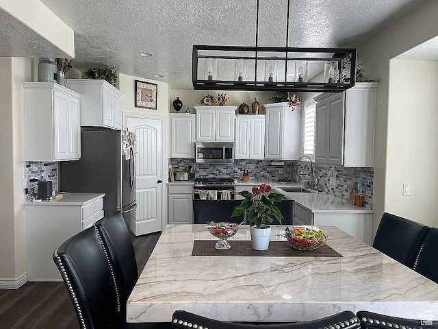 kitchen with sink, pendant lighting, white cabinets, and dark wood-type flooring