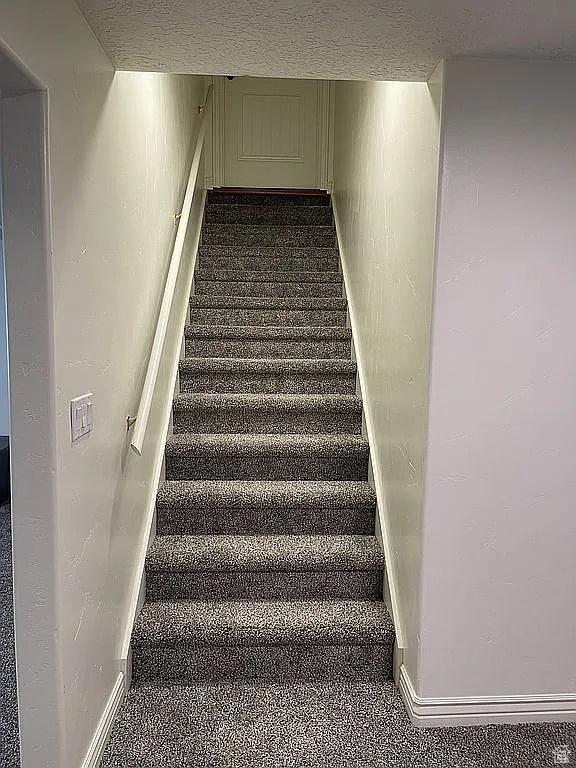 stairway featuring a textured ceiling