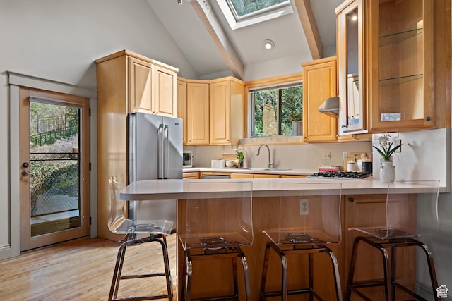 1204 E Gilmer Dr, Salt Lake City, UT 84105 - kitchen with a peninsula, light countertops, extractor fan, a kitchen bar, and lofted ceiling with skylight