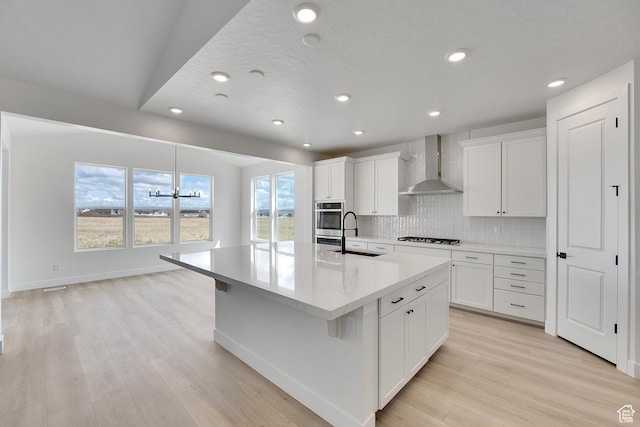6184 W Teton Ranch Dr S Unit 304, Herriman, UT 84096 - kitchen featuring wall chimney range hood, stainless steel oven, a sink, gas stovetop, and a kitchen island with sink