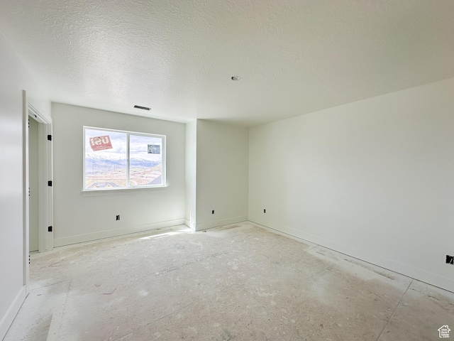 empty room featuring baseboards and a textured ceiling