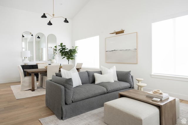 living room with baseboards, high vaulted ceiling, and light wood-style floors