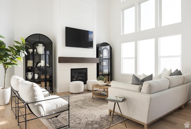living room featuring a high ceiling, wood finished floors, and a tiled fireplace