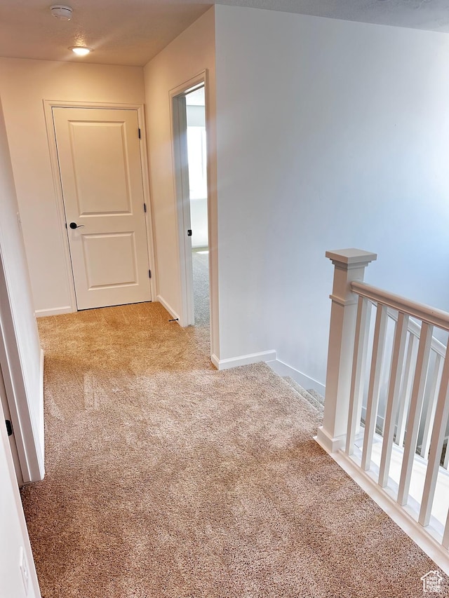 hall with carpet, an upstairs landing, and baseboards