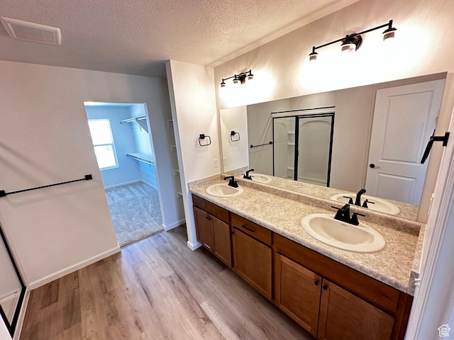 full bath featuring a textured ceiling, wood finished floors, and double vanity