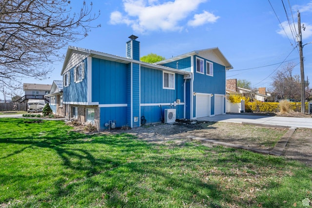rear view of property with ac unit, a lawn, an attached garage, a chimney, and concrete driveway