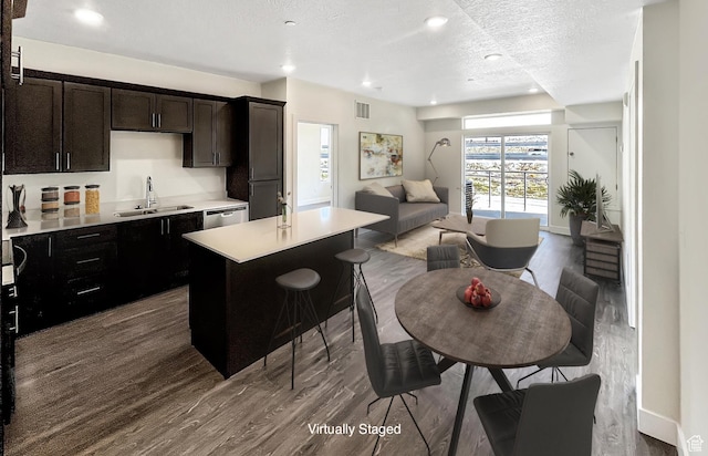 kitchen with open floor plan, light countertops, a center island, a sink, and visible vents