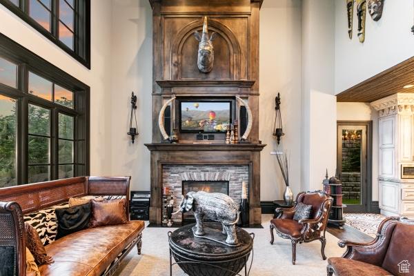 sitting room with carpet floors, a fireplace, and a towering ceiling