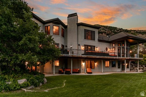 back house at dusk with an outdoor living space, a yard, and a patio area