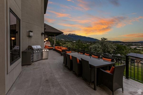 patio terrace at dusk with area for grilling, a mountain view, an outdoor hangout area, and an outdoor kitchen