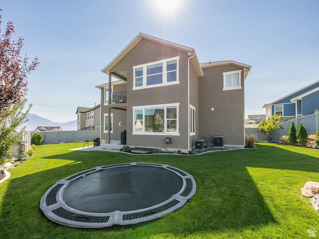 668 W Leroy Cir, Saratoga Springs, UT 84045 - back of house featuring a balcony, a trampoline, a fenced backyard, stucco siding, and a lawn