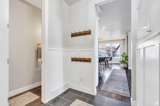 668 W Leroy Cir, Saratoga Springs, UT 84045 - hallway featuring dark tile patterned flooring, a wainscoted wall, visible vents, a decorative wall, and a notable chandelier
