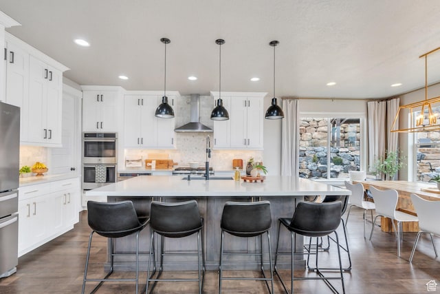 668 W Leroy Cir, Saratoga Springs, UT 84045 - kitchen with light countertops, double oven, a breakfast bar, wall chimney range hood, and a kitchen island with sink