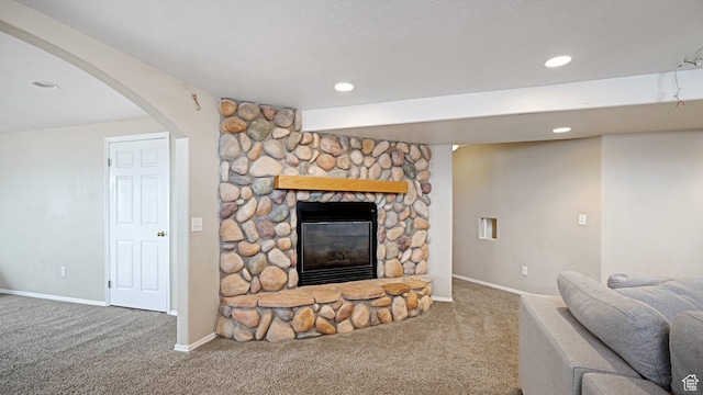 carpeted living room featuring a stone fireplace
