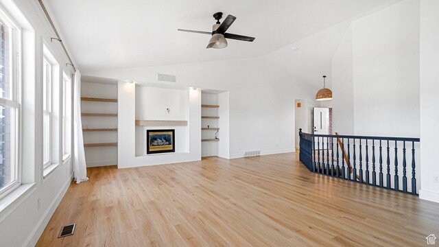unfurnished living room featuring built in shelves, ceiling fan, lofted ceiling, and light hardwood / wood-style floors