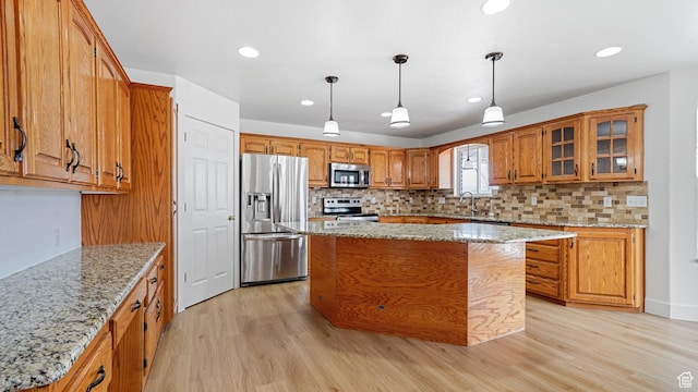 kitchen featuring a kitchen island, appliances with stainless steel finishes, light stone counters, and light hardwood / wood-style flooring