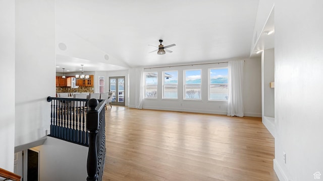 living room featuring light hardwood / wood-style flooring, ceiling fan with notable chandelier, plenty of natural light, and vaulted ceiling