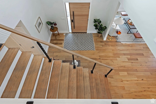 foyer entrance featuring baseboards, wood finished floors, and stairway