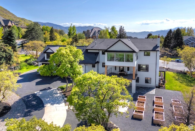 view of front of property with a mountain view, stucco siding, stairs, and a garden