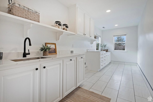 kitchen with a sink, open shelves, white cabinetry, and light countertops