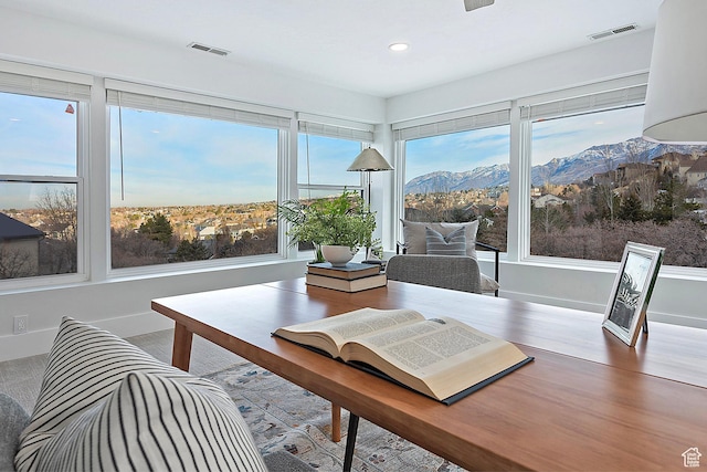 sunroom with visible vents, a mountain view, and a wealth of natural light