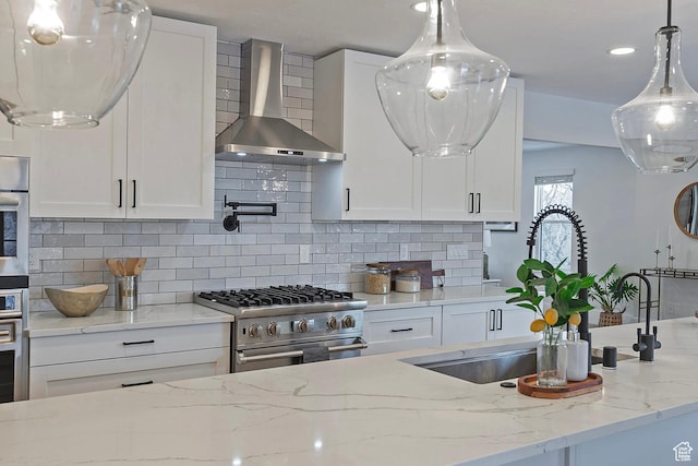 kitchen featuring wall chimney range hood, stainless steel appliances, and white cabinetry