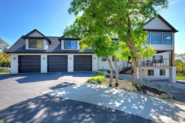 view of front of home featuring a garage, stairs, a shingled roof, and driveway