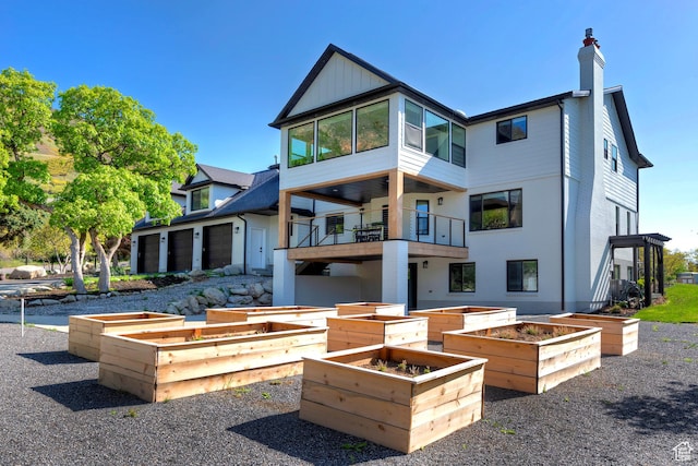 rear view of property with a chimney, a vegetable garden, and a balcony