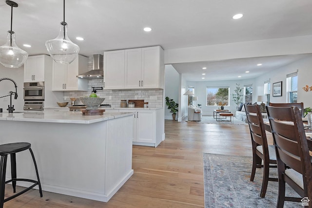 kitchen featuring recessed lighting, wall chimney exhaust hood, and white cabinetry