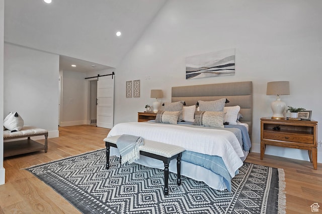 bedroom featuring baseboards, high vaulted ceiling, recessed lighting, a barn door, and light wood-type flooring
