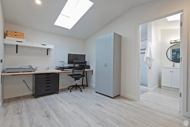 office space featuring light wood-type flooring, recessed lighting, a sink, and vaulted ceiling with skylight