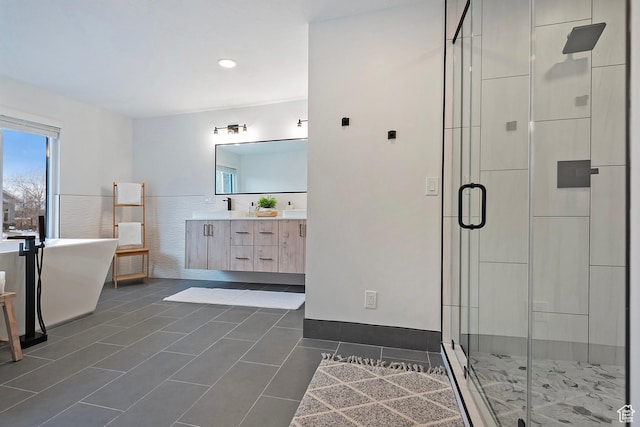 bathroom featuring a freestanding bath, tile patterned flooring, double vanity, a wainscoted wall, and a shower stall