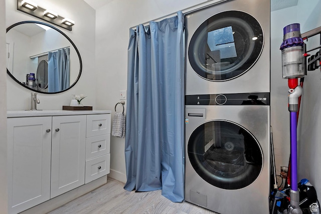 laundry area featuring a sink, stacked washer / drying machine, and light wood-style flooring