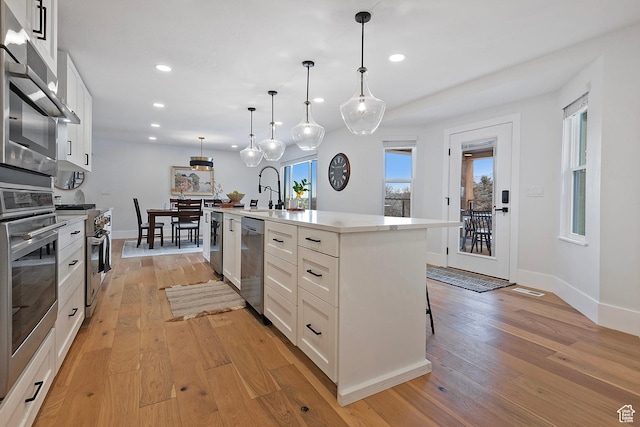 kitchen featuring recessed lighting, appliances with stainless steel finishes, a sink, and light wood-type flooring