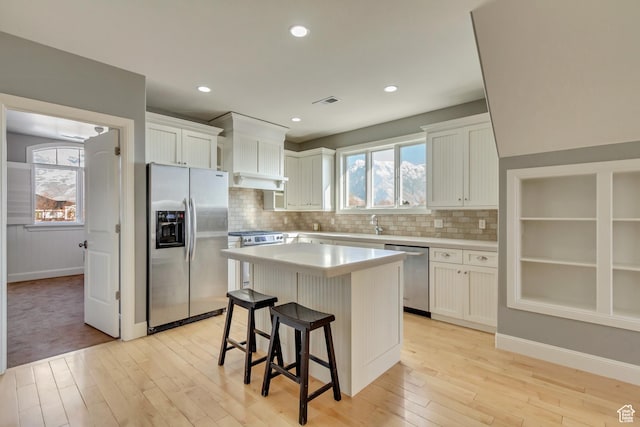 kitchen with white cabinetry, a kitchen bar, a center island, and appliances with stainless steel finishes