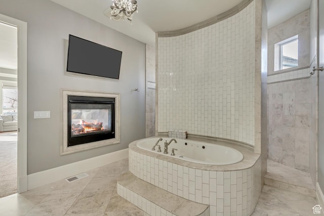 bathroom featuring plenty of natural light and tiled bath