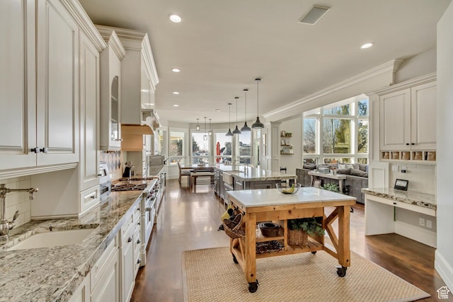 kitchen with a kitchen island, sink, hanging light fixtures, stainless steel range, and plenty of natural light