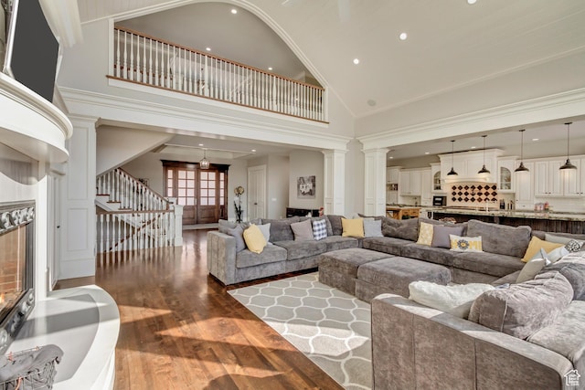 living room featuring hardwood / wood-style flooring, high vaulted ceiling, and ornate columns