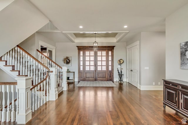 foyer featuring a raised ceiling, crown molding, dark hardwood / wood-style floors, and french doors