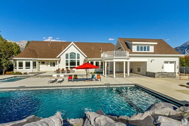 back of property featuring a balcony, a mountain view, and a patio area