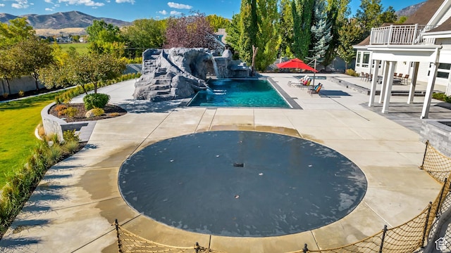 view of swimming pool with a patio, a mountain view, and pool water feature