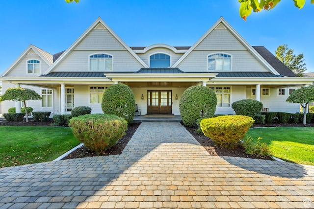 view of front of property featuring french doors, a porch, and a front lawn