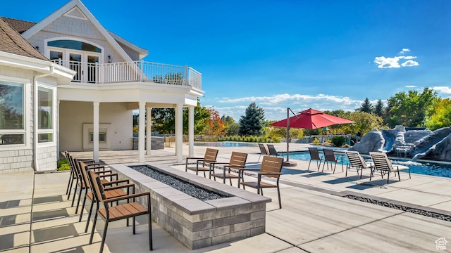 view of patio / terrace featuring pool water feature, a balcony, and a fire pit