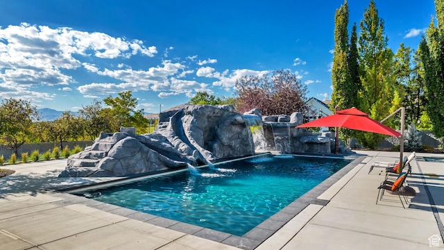 view of swimming pool with pool water feature and a patio area