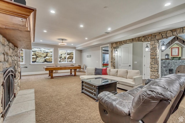 carpeted living room with a stone fireplace, ornamental molding, and pool table