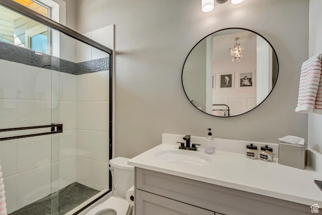 bathroom featuring vanity, a shower with shower door, toilet, and an inviting chandelier