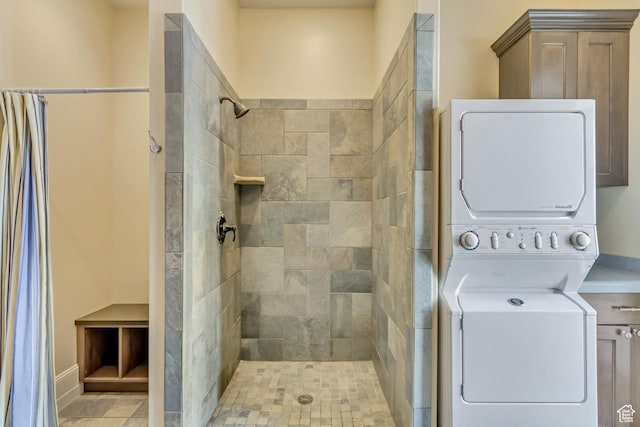 bathroom with stacked washer / dryer and a tile shower