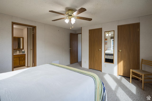 carpeted bedroom featuring ceiling fan, a textured ceiling, and ensuite bath